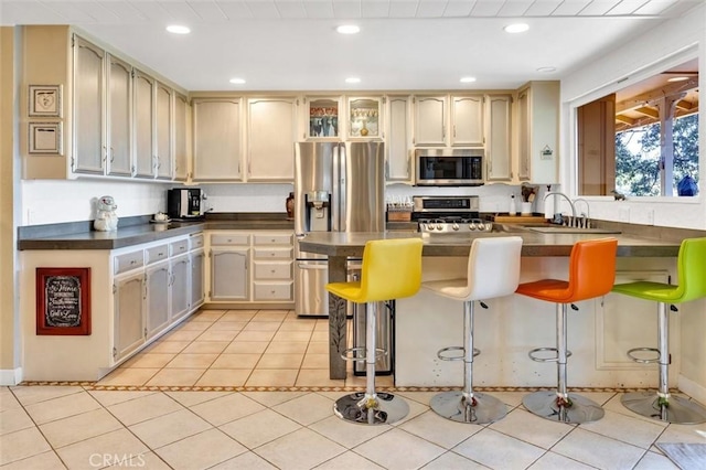 kitchen with light tile patterned flooring, a breakfast bar area, appliances with stainless steel finishes, and sink