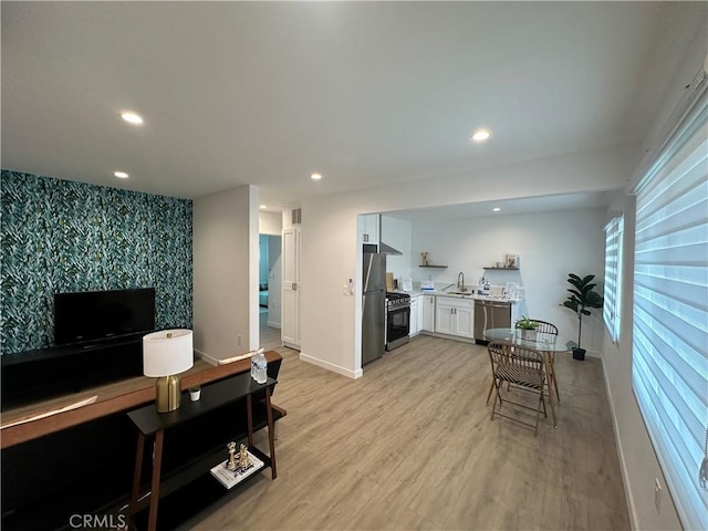 kitchen with sink, white cabinets, light wood-type flooring, and appliances with stainless steel finishes