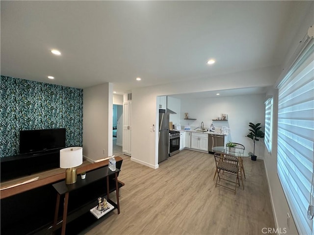 kitchen featuring a wealth of natural light, sink, light hardwood / wood-style flooring, white cabinets, and appliances with stainless steel finishes