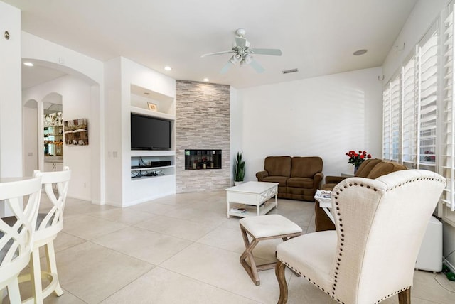 living room with ceiling fan, a large fireplace, light tile patterned floors, and built in features