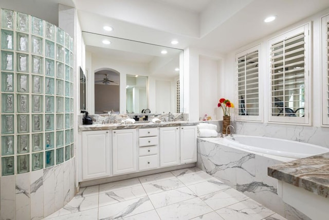 bathroom featuring vanity, ceiling fan, and a relaxing tiled tub