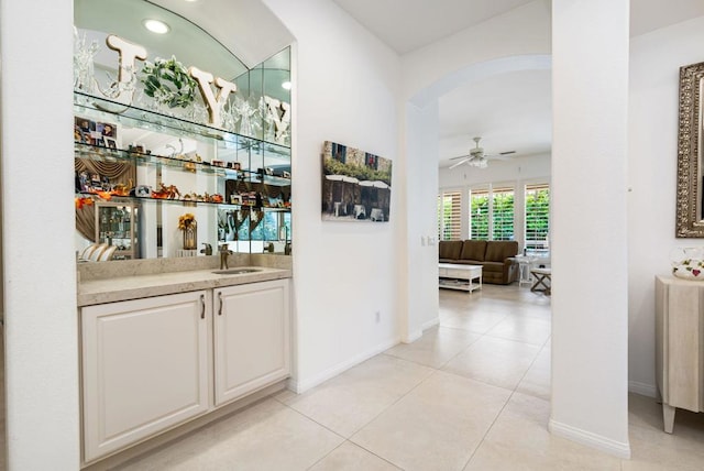 bar featuring sink, light tile patterned flooring, white cabinets, and ceiling fan