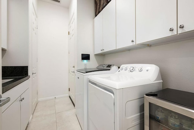 laundry room featuring light tile patterned flooring, cabinets, and washing machine and clothes dryer