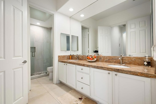 bathroom featuring a shower with door, toilet, vanity, and tile patterned flooring