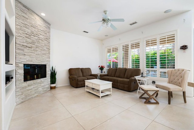 tiled living room featuring ceiling fan and a fireplace