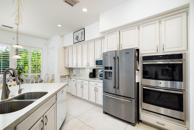 kitchen featuring pendant lighting, appliances with stainless steel finishes, white cabinetry, sink, and light tile patterned flooring