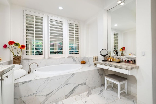 bathroom with vanity, tiled tub, and plenty of natural light