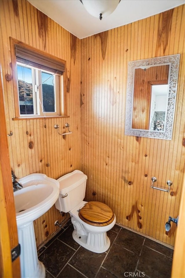 bathroom with toilet and wood walls