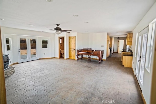 unfurnished living room with a wood stove and ceiling fan