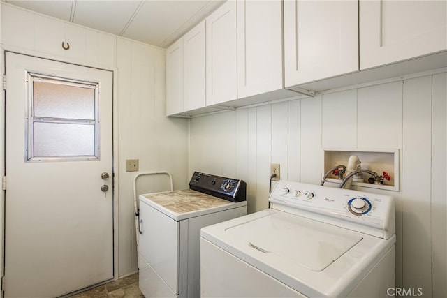 laundry area with cabinets, wood walls, and washing machine and dryer