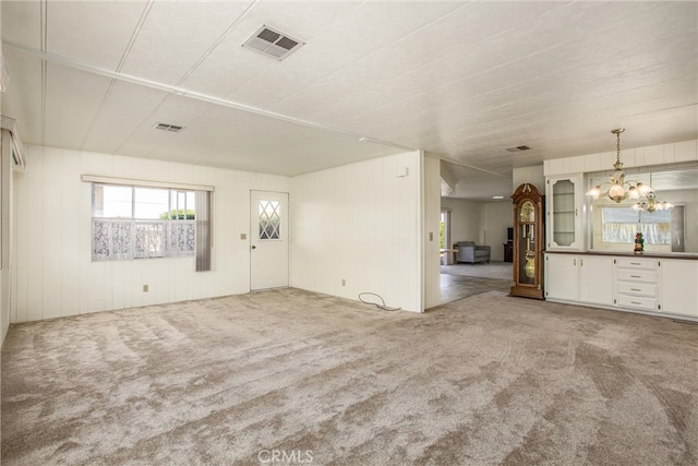 unfurnished living room with light carpet and an inviting chandelier