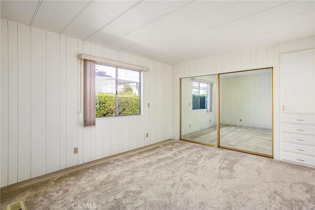 unfurnished bedroom featuring wooden walls, a closet, and carpet