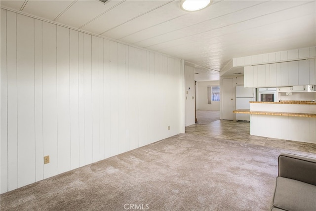 unfurnished living room with wood walls and light carpet