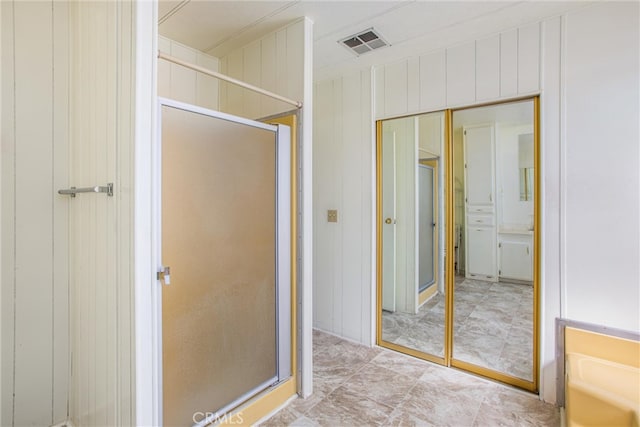 bathroom featuring wood walls and an enclosed shower