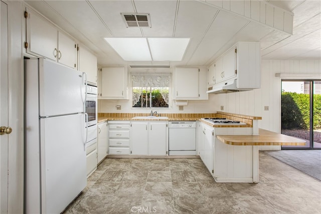 kitchen with white appliances, white cabinetry, sink, and a kitchen breakfast bar