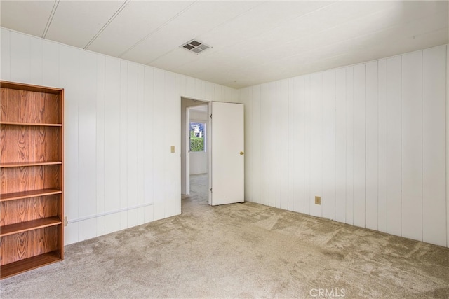 carpeted empty room featuring wood walls