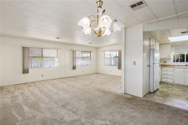 interior space featuring a chandelier, light colored carpet, sink, and wooden walls