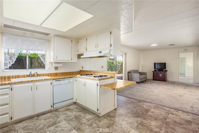 kitchen featuring white appliances, light carpet, kitchen peninsula, premium range hood, and white cabinetry