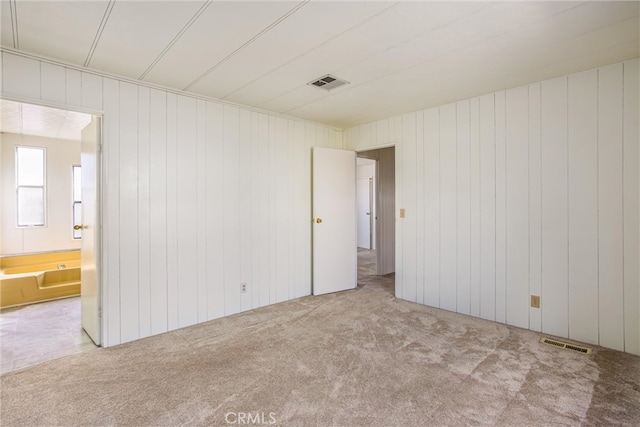 empty room featuring light carpet and wood walls