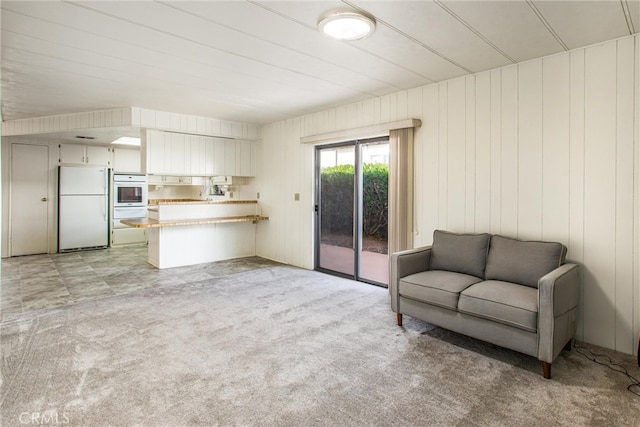 living room featuring wooden walls and light carpet