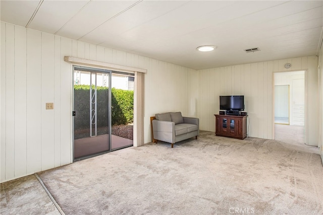 unfurnished living room with wooden walls and carpet