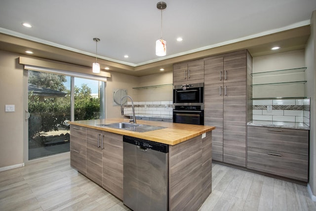 kitchen featuring dishwasher, light hardwood / wood-style floors, tasteful backsplash, sink, and a center island with sink