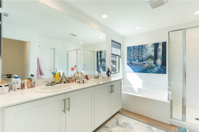 bathroom with wood-type flooring, vanity, and independent shower and bath