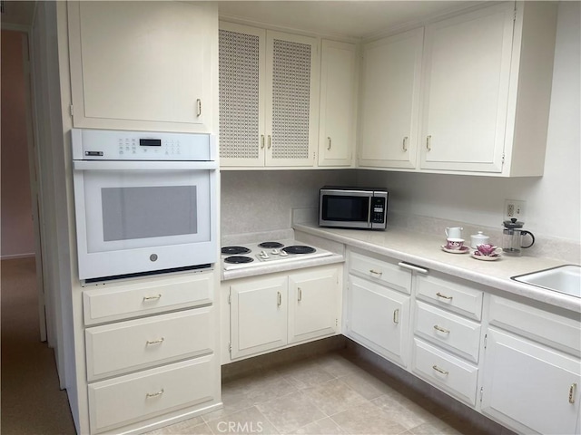 kitchen featuring white cabinets, light tile patterned floors, and white appliances