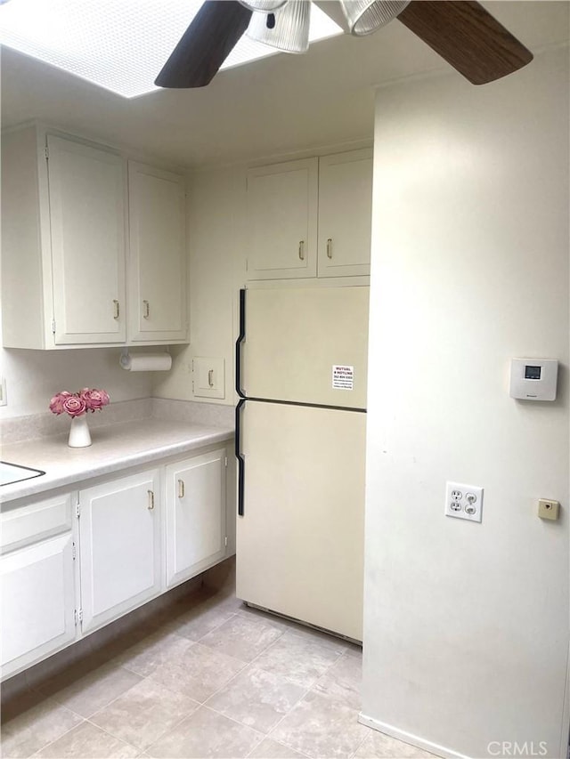 kitchen featuring ceiling fan, white refrigerator, and white cabinetry