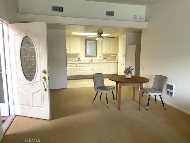 dining area featuring ceiling fan, sink, and light carpet