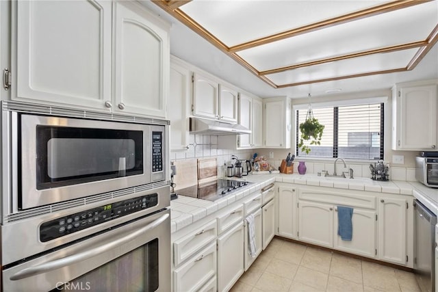 kitchen with white cabinetry, sink, tile countertops, decorative backsplash, and appliances with stainless steel finishes