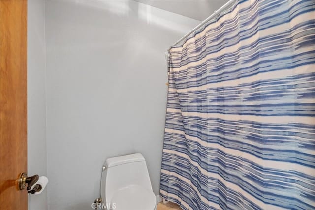 bathroom featuring a shower with shower curtain and toilet