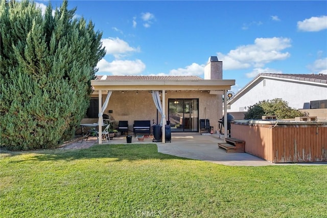 rear view of house featuring a yard, a patio, and a hot tub