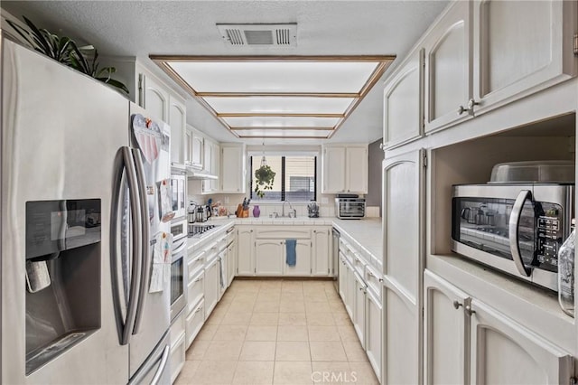 kitchen with white cabinetry, sink, a textured ceiling, light tile patterned floors, and appliances with stainless steel finishes