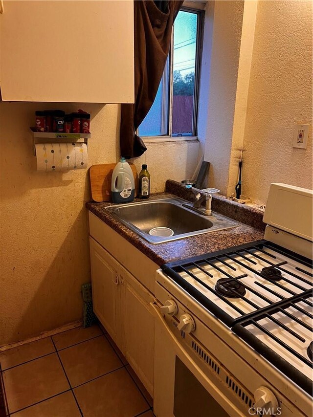 kitchen featuring light tile patterned flooring, range, and sink