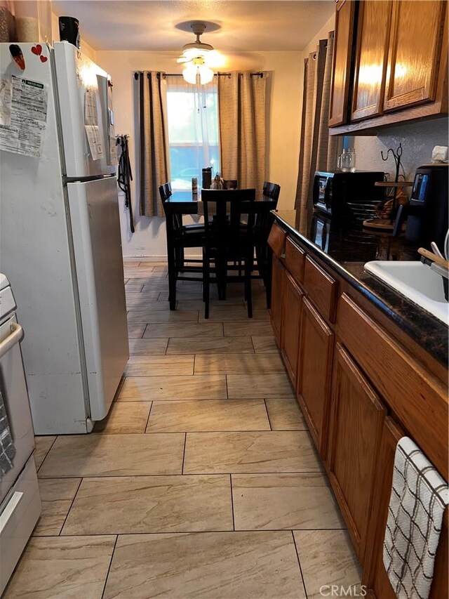 kitchen with ceiling fan, white refrigerator, range, and sink