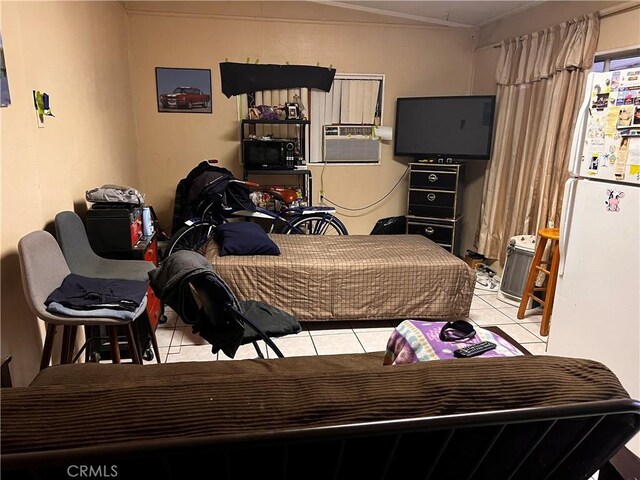 bedroom featuring light tile patterned floors, white fridge, and cooling unit