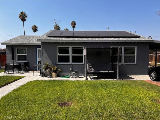 view of front of house with solar panels, a patio, and a front lawn