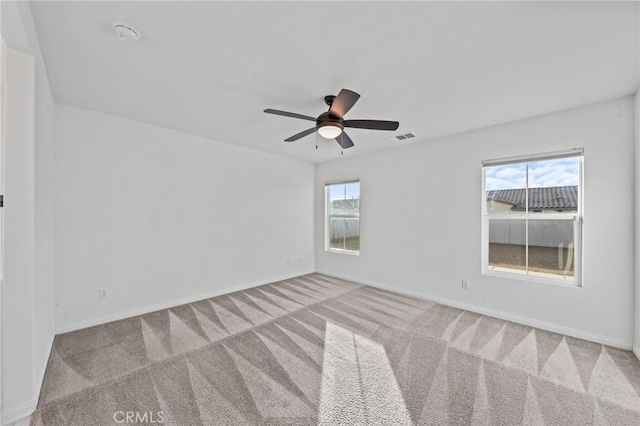 carpeted empty room featuring ceiling fan and a wealth of natural light