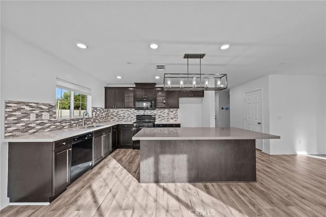 kitchen featuring sink, black appliances, a center island, light hardwood / wood-style floors, and hanging light fixtures