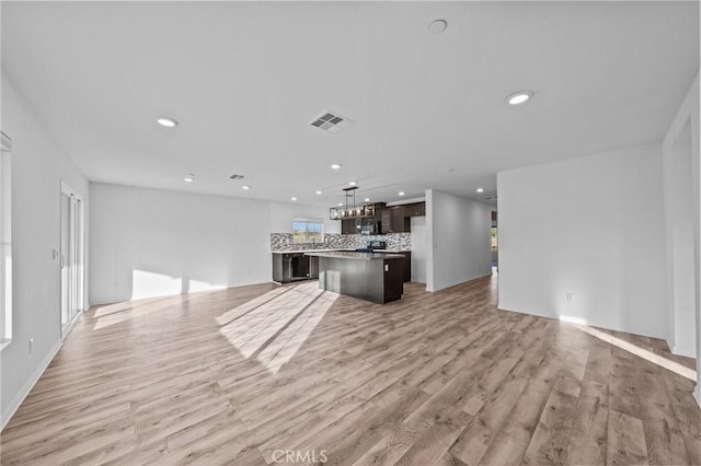 unfurnished living room featuring plenty of natural light and light hardwood / wood-style floors