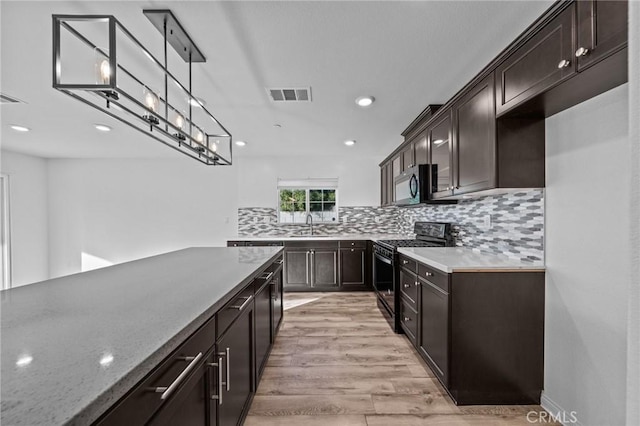 kitchen featuring stainless steel appliances, light hardwood / wood-style floors, decorative light fixtures, decorative backsplash, and dark brown cabinets