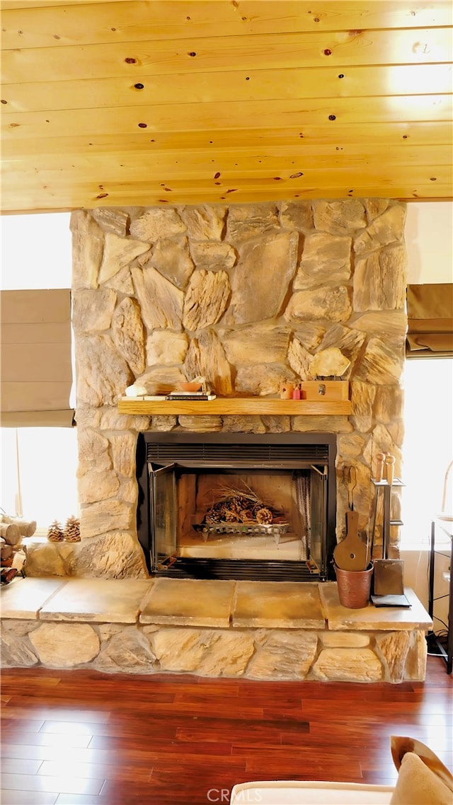 interior details with wood ceiling, a stone fireplace, and hardwood / wood-style flooring