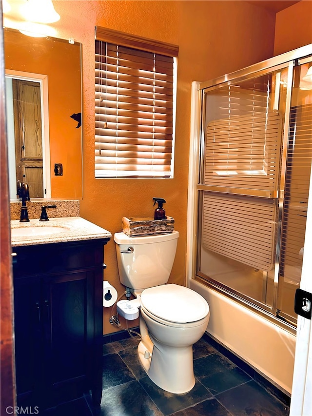 full bathroom with enclosed tub / shower combo, vanity, and toilet