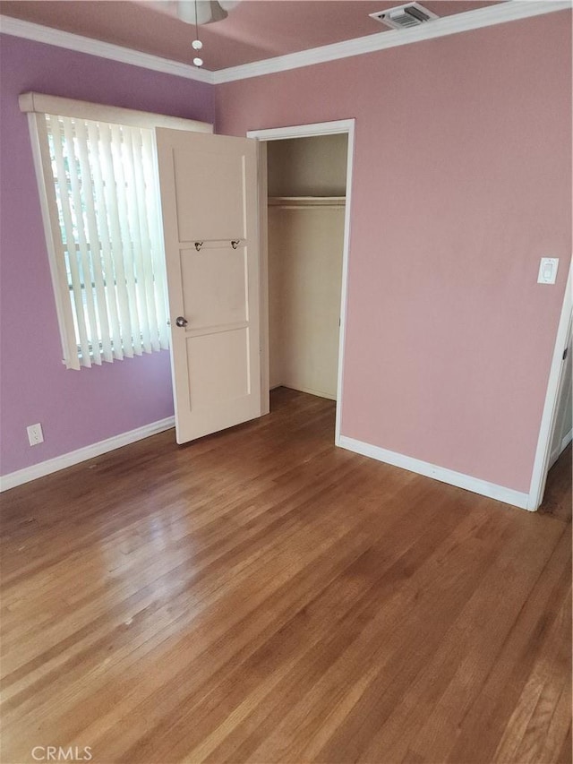 unfurnished bedroom featuring crown molding, a closet, and hardwood / wood-style flooring