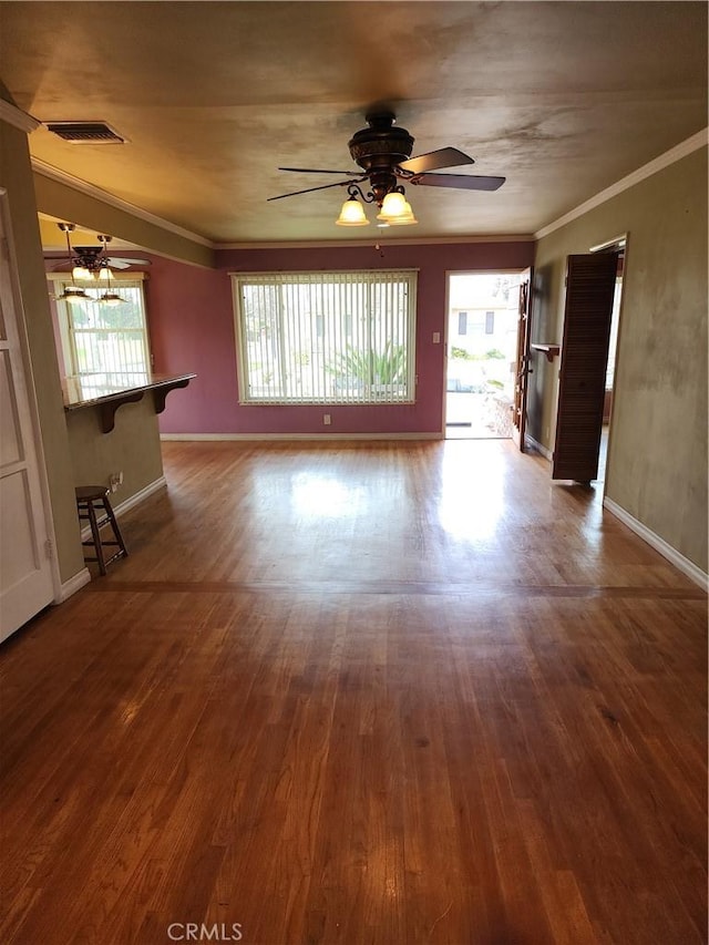 unfurnished living room with ornamental molding, a healthy amount of sunlight, visible vents, and wood finished floors