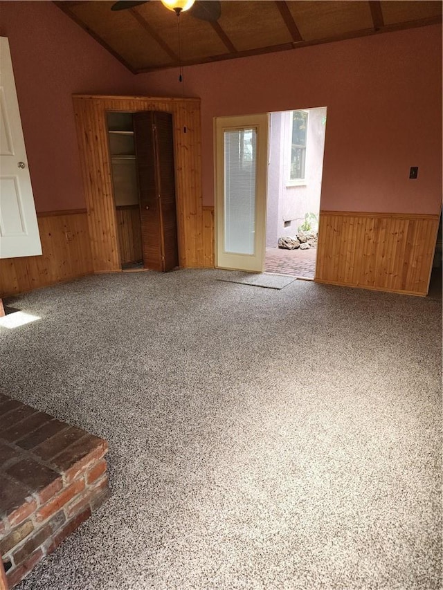 carpeted empty room featuring ceiling fan, wooden walls, and wainscoting