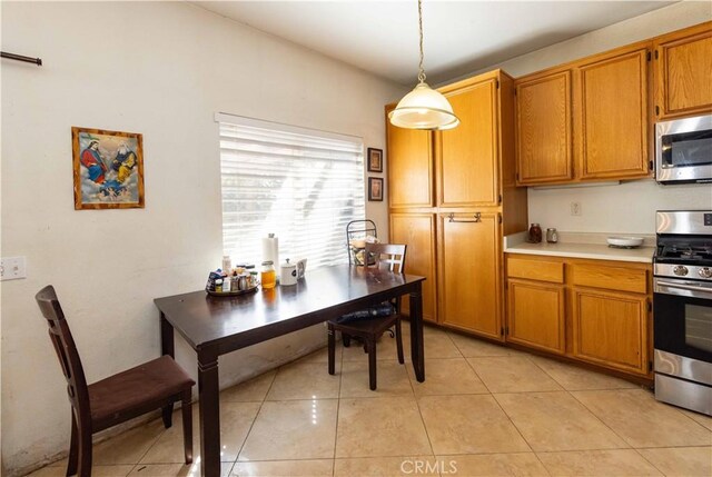 kitchen with light tile patterned flooring, stainless steel appliances, and hanging light fixtures