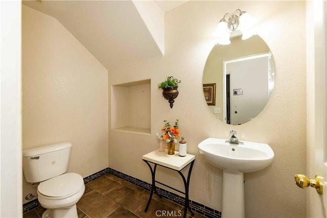 bathroom featuring tile patterned flooring, toilet, sink, and vaulted ceiling