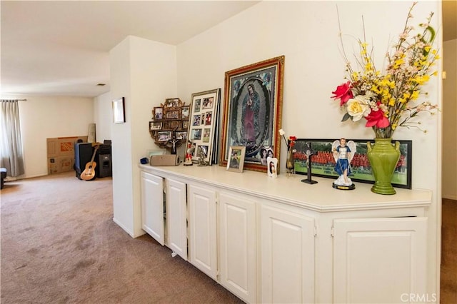 bar featuring white cabinets and light colored carpet